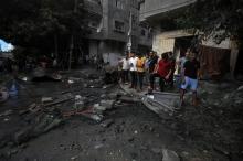 Photo: Palestinians observe the remains of a five-storey house after it was bombed by the Israeli military on Al-Nasr Street near Al-Quds Open University, west of Gaza City. (Credit: Mohamed Zaanoun).