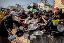People displaced from their homes waiting for food at Al-Shaboura Camp, in the centre of Rafa, Gaza on 17–18 December 2023.